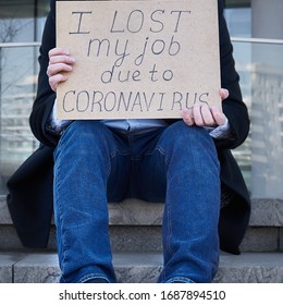 Job loss due to COVID-19 virus pandemic concept. Unrecognizable man holds sign "I lost my job because of coronavirus." Male sitting on stairs of building, former place of work in business center