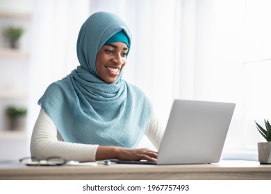 Job Opportunities For Muslim Women. Portrait Of Smiling Black Islamic Woman In Hijab Working On Laptop In Office, Religious African Lady In Headscarf Sitting At Desk And Using Computer, Copy Space