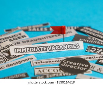 Jobs Or Careers Concept: Multiple Job Titles Or Occupations Cut Off From Newspaper With Immediate Vacancies At The Centre Of The Pile, Blue Background