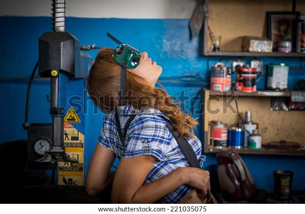 Jobs in\
the service station. The girl in the mask working at the bench.\
Hard work for women, fatigue, seven days a\
week