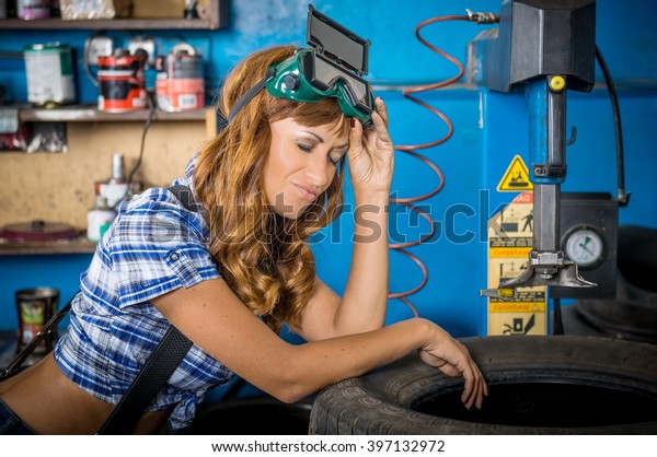 Jobs in the service station. The girl in the mask\
working at the bench. Hard work for women, seven days a week.\
Female mechanic at work. auto service station, working girl. woman\
working in garage