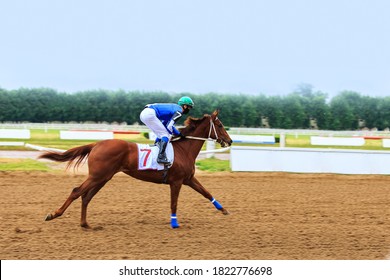 A Jockey Rides A Brown Horse On A Racetrack On A Sandy Starting Track