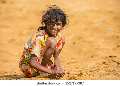 Jodhpur, rajasthan, india - june 18th, 2019: Poor rural girl playing with sand in hot summer, smiling towards camera, poverty unprivileged indian children.