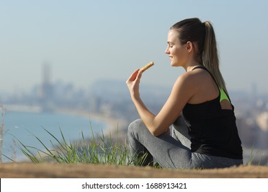 Jogger Eating Energy Bar After Sport Sitting Outdoors In A City Outskirts