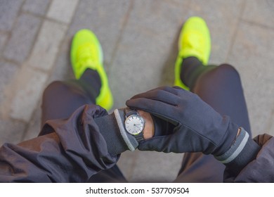 Jogger making a pause in the park and checking his running time.
