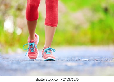 Jogging woman with athletic legs and running shoes. Female walking on trail in forest in healthy lifestyle concept with close up on running shoes. Female athlete jogger training outdoors.