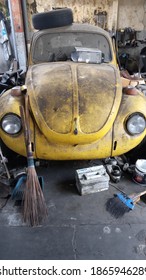 Jogja 2 Dec 2020 - A Local Garage Is Preparing An Old Yellow Volkswagen Beetle Car Right Inside The Messy Garage During Hot Afternood Day