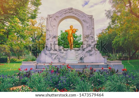 Johann Strauss monument in Vienna, Austria. Famous golden statue of great Austrian composer, waltz king, playing violin. Autumn green city park stadtpark in Vienna at sunny day. Golden fiddler statue