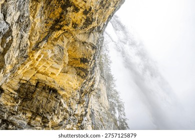 Johannes Waterfall flows dramatically down rocky cliffs surrounded by lush greenery in Obertauern, Austria. Mist envelops the scene, creating a serene atmosphere.