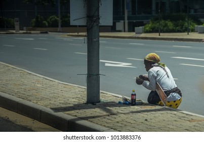 Johannesburg, Gauteng / South Africa - 31 DEC 2017: Female Beggar Sitting Down Eating And Drinking On The Pavement