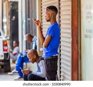 Johannesburg, South Africa, January 24 2017, African Men Using Their Mobile Phones On A Side Walk