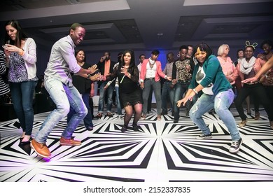 JOHANNESBURG, SOUTH AFRICA - Mar 24, 2022: A Group Of Diverse People Dancing On A Black And White Geometric Dance Floor