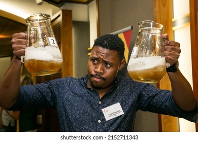 JOHANNESBURG, SOUTH AFRICA - Mar 24, 2022: A Closeup Of An African Barman Holding Two Jars Of Beer In Hands And Looking Curiously