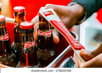 Johannesburg, South Africa - March 27, 2018: African Barman Opening A Budweiser Bottles Of Beer In Red Branded Ice Bucket On Bar Counter