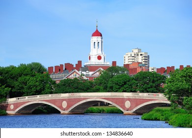 John W. Weeks Bridge and clock tower over Charles River in Harvard University campus in Boston with trees and blue sky.