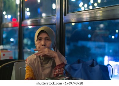 JOHOR BARU,MALAYSIA-JUNE 5 2020: A Close Up View Of A Lonely Old Malay Woman In 60's Inside A Restaurant With Light Reflection Over The Window Glass