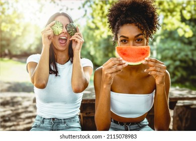 joiful multicultural young adult girlfriends sitting countryside under the trees eating fresh watermelon and hiding the faces with slices and peel - genz women sustainable lifestyle