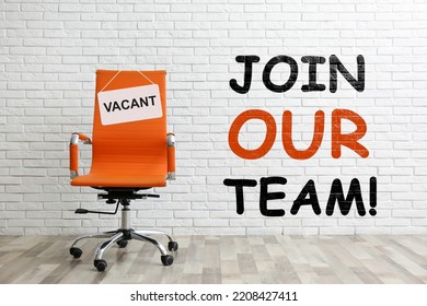 Join Our Team! Orange Office Chair With Sign VACANT Near White Brick Wall Indoors