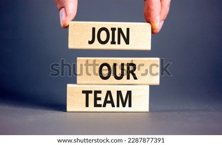 Join our team symbol. Concept words Join our team on wooden block on a beautiful grey table grey background. Businessman hand. Business and join our team concept. Copy space.