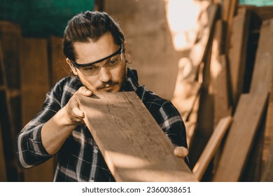 Joiner furniture maker worker choice select wood material from pile stock to find wood piece that suitable for new projects. - Shutterstock ID 2360038651