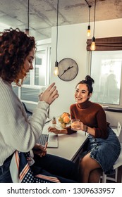 Joining Friend. Curly Red-haired Roommate Joining Her Friend In The Kitchen And Drinking Orange Juice