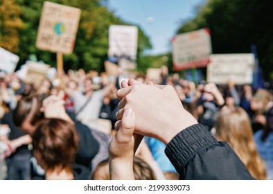 joining hands at a rally against climate change, signaling peace, unity and decisiveness in front of a crowd carrying protest placards with shallow depth of field - Powered by Shutterstock