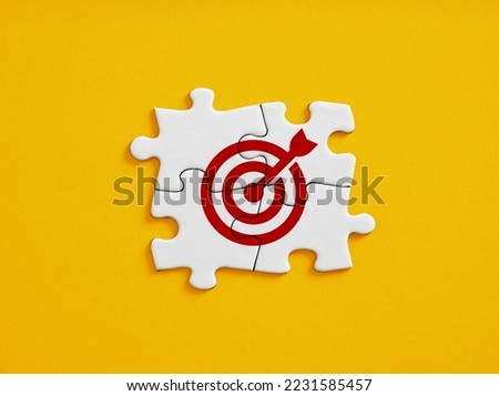 Joint effort or teamwork for achieving target goal objectives in business. Initiation and synergy to reach target. Objective, goal or target icon on connected jigsaw puzzle pieces.