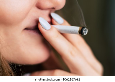 a joint in hand A woman smokes cannabis weed, . Smoke on a black background. Concepts of medical marijuana use and legalization of the cannabis. On a black background