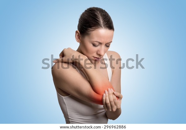 「関節の炎症は、女性の肘に赤い斑点を示している。腕の痛みとけがのコンセプト。青の背景に痛い肘を持つ接写の女性」の写真素材（今すぐ編集