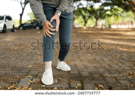 Joint pain, Arthritis and tendon problems. an asian muslim woman touching knee at pain point in the park. Close up photo