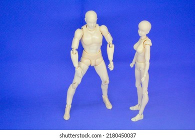 Jointed male and female wooden mannequins are isolated on a blue background. Selective focus