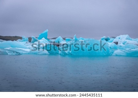 Jokulsarlon glacial lagoon in Iceland, with luminous blue icebergs from retreating glacier drifting towars the Atlantic Ocean.