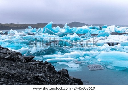Jokulsarlon glacial lagoon in Iceland, with luminous blue icebergs from retreating glacier drifting towars the Atlantic Ocean.