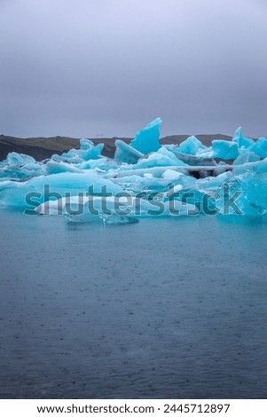 Jokulsarlon glacial lagoon in Iceland, with luminous blue icebergs from retreating glacier drifting towars the Atlantic Ocean and seals swimming around.
