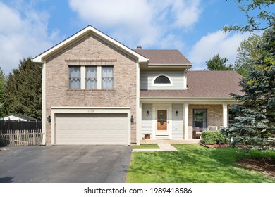 JOLIET, IL, USA - APRIL 20, 2021: A New Suburban House With Half Grey Siding And Half Brick, A Covered Front Porch, And Wooden Front Door.