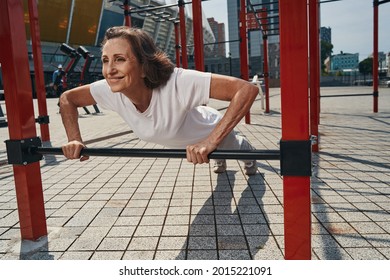 Jolly active mature lady training upper body outdoors - Powered by Shutterstock