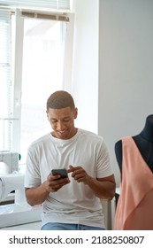 Jolly African American Tailor Using Cell Phone In Workshop