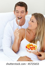 Jolly Couple Eating Fruit Lying On Their Bed At Home