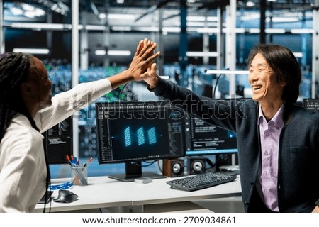 Jolly data center programmers doing high five, happy after finishing AI training. Delighted coworkers celebrate after deploying neural networks in server hub with scalable infrastructure for AI apps