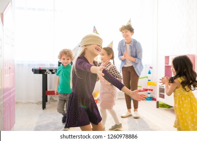 Jolly Excited Girl In Eye Patch Running Over Room And Keeping Arms Outstretched While Catching Up With Friends During Blind Mans Buff