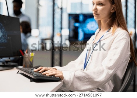 Jolly junior dev in office using AI on computer to streamline app development. Young female engineer at desk using PC to run debugging programs with machine learning technology