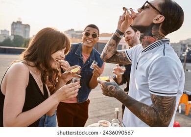 jolly multicultural people in vibrant clothes enjoying tequila with salt and lime at rooftop party - Powered by Shutterstock