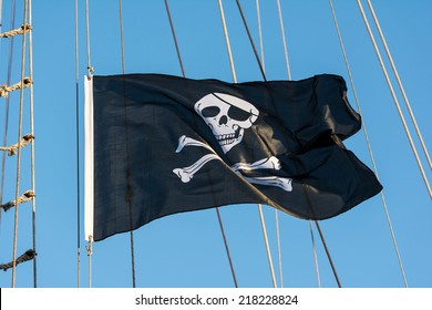 Jolly Roger Black Pirate Flag With Human Skull On Blue Sky