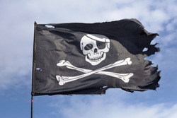 Jolly Roger. Pirate Flag.Against The Background Of Blue Sky.