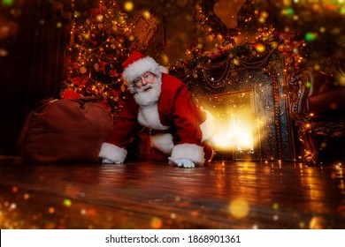 Jolly Santa Claus sneaked into the house through the fireplace with a bag of gifts. Beautiful home decoration. Merry Christmas and Happy New Year! - Shutterstock ID 1868901361