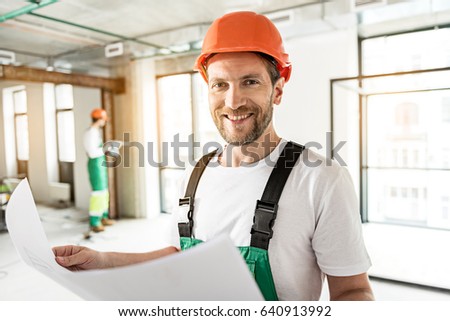 Jolly smiling builder keeping drafts