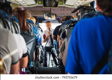 Jordan, Akaba - December 19, 2017: Tourists And A Male Tour Guide With A Microphone In The Bus