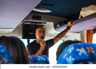 Jordan, Akaba - December 25, 2017: Male Tour Guide With A Microphone In The Touristic Bus