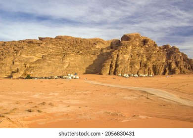 Jordan - Wadi Rum - The spectacular mountain landscape of Wadi Rum desert with bedouin camp luxury bubble ufo-like tents in the distance at sunset