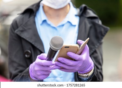 Journalist Wearing Protective Gloves And Face Mask Against Coronavirus COVID-19 Disease Holding Microphone Making Media Interview During Virus Pandemic